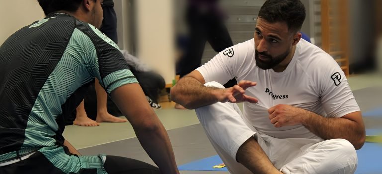 Un coach de Jiu-Jitsu brésilien expliquant des techniques de combat à un élève attentif lors d’une session d’entraînement.